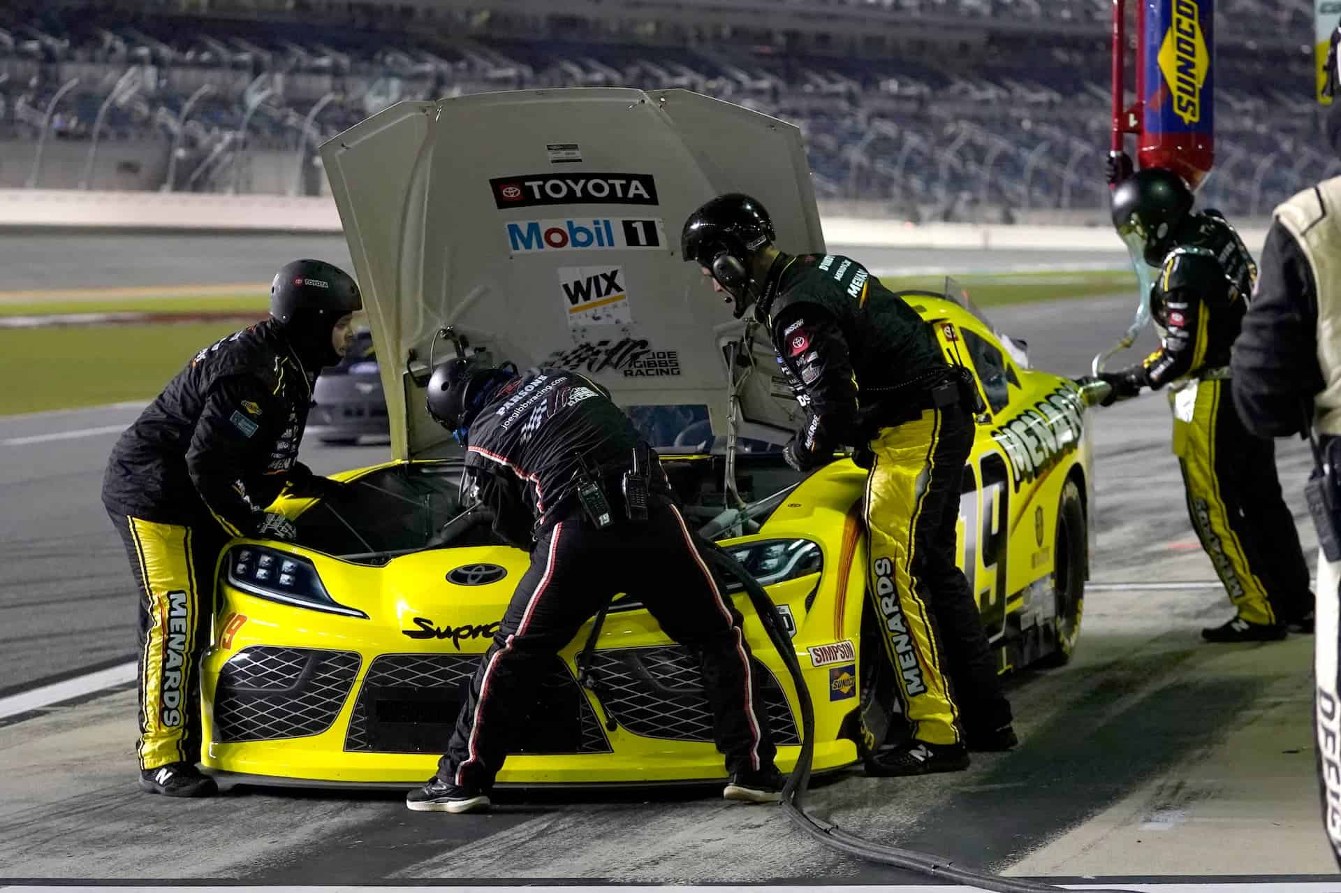 Brandon Jones sits on pit road at Daytona International Speedway. The No. 19 crew works under the hood to address an overheating issue after debris covered the front grill.