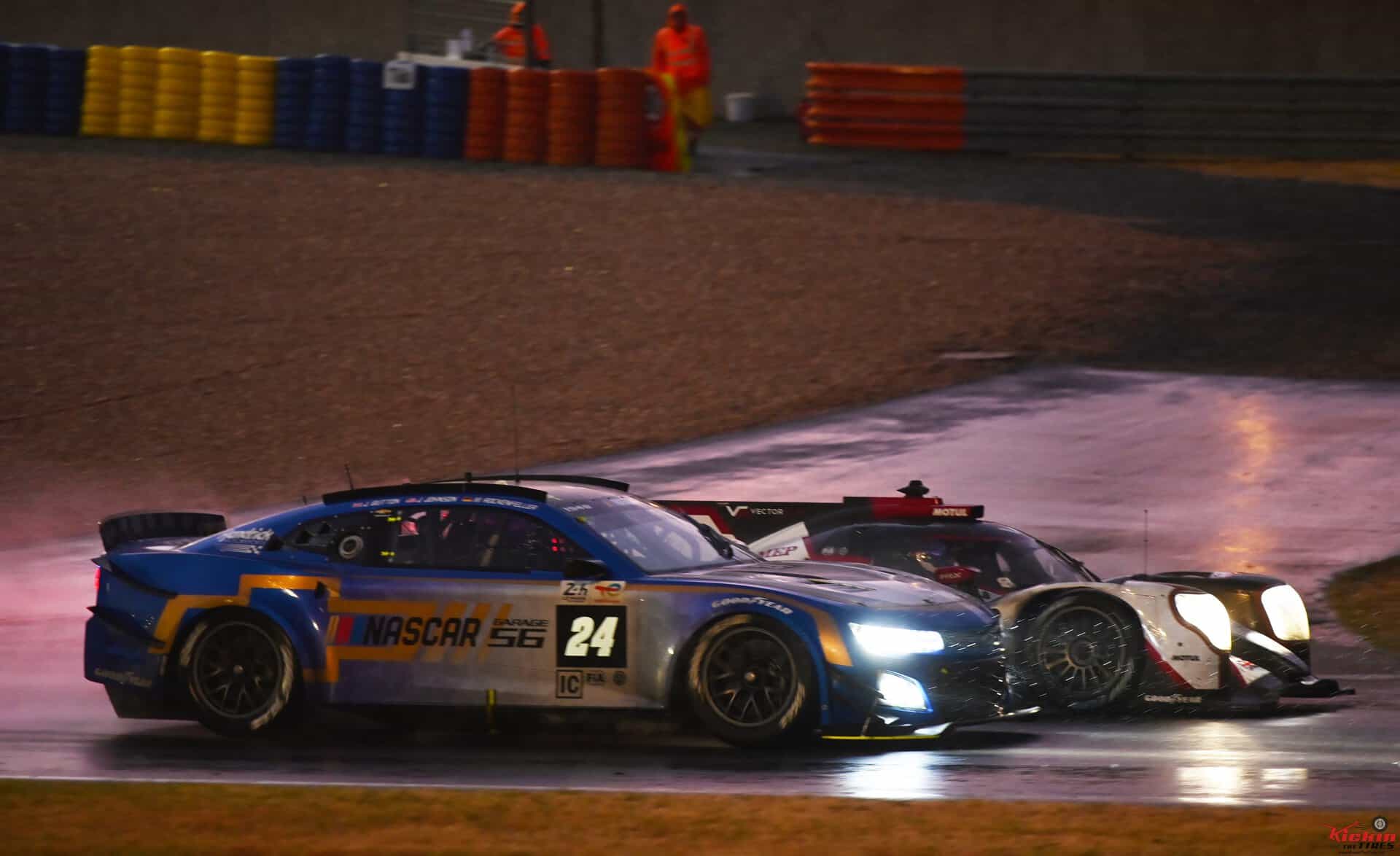 The NASCAR Garage 56 Camaro battles with a Prototype at night in the rain during the 24 Hours of Le Mans.