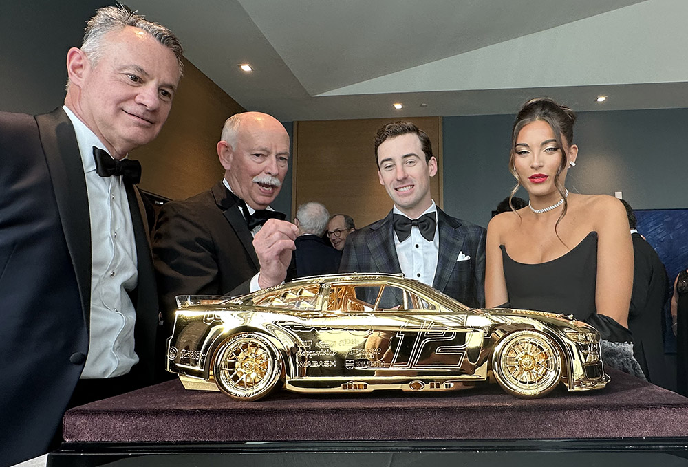 Rich kramer (left), along with goodyear's stu grant, 2023 cup series champion ryan blaney and gianna tulio check out the amazing craftsmanship of the goodyear gold car trophy. Photo by jerry jordan/kickin' the tires