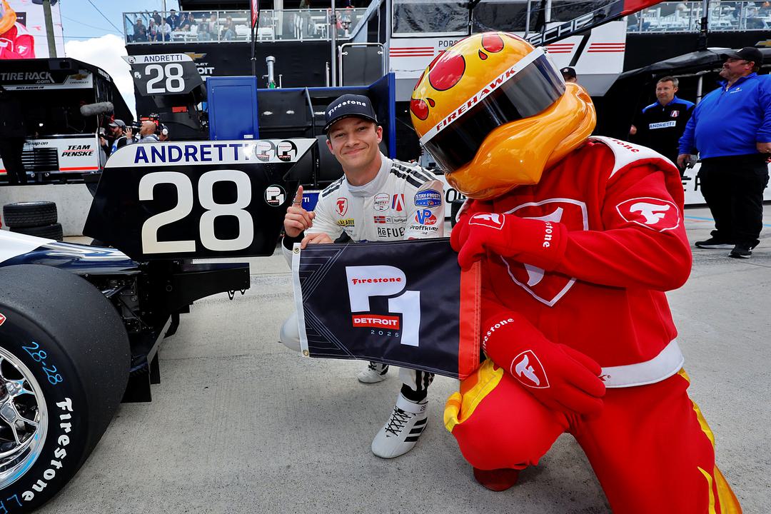 Dennis Hauger poses with Firestone Firehawk mascot after taking INDY NXT pole in Detroit.
