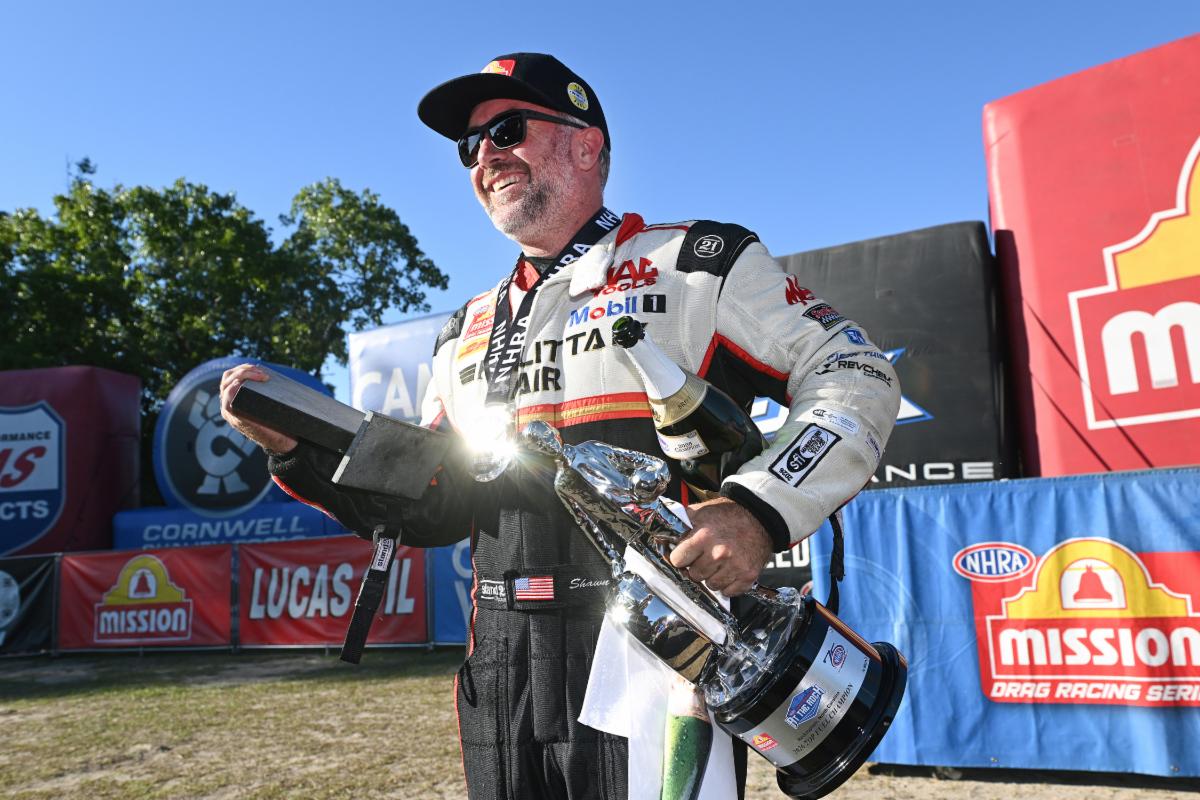 Shawn langdon celebrates with the wally trophy after a 2026 nhra top fuel victory.